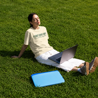 Person sitting on grass with a laptop, wearing a 'Gold Day Off' t-shirt