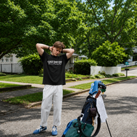 Person stretching with a golf bag and clubs on a residential street