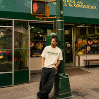Man standing under a green awning with a store sign in the background