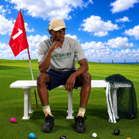 Man sitting on a golf course bench with golf balls and equipment around, under a blue sky.