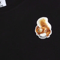 Squirrel close-up – Embroidered squirrel detail sitting on a golf ball on a black cotton T-shirt