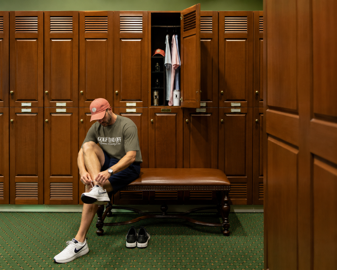 Man sitting on a bench in a locker room with wooden lockers.