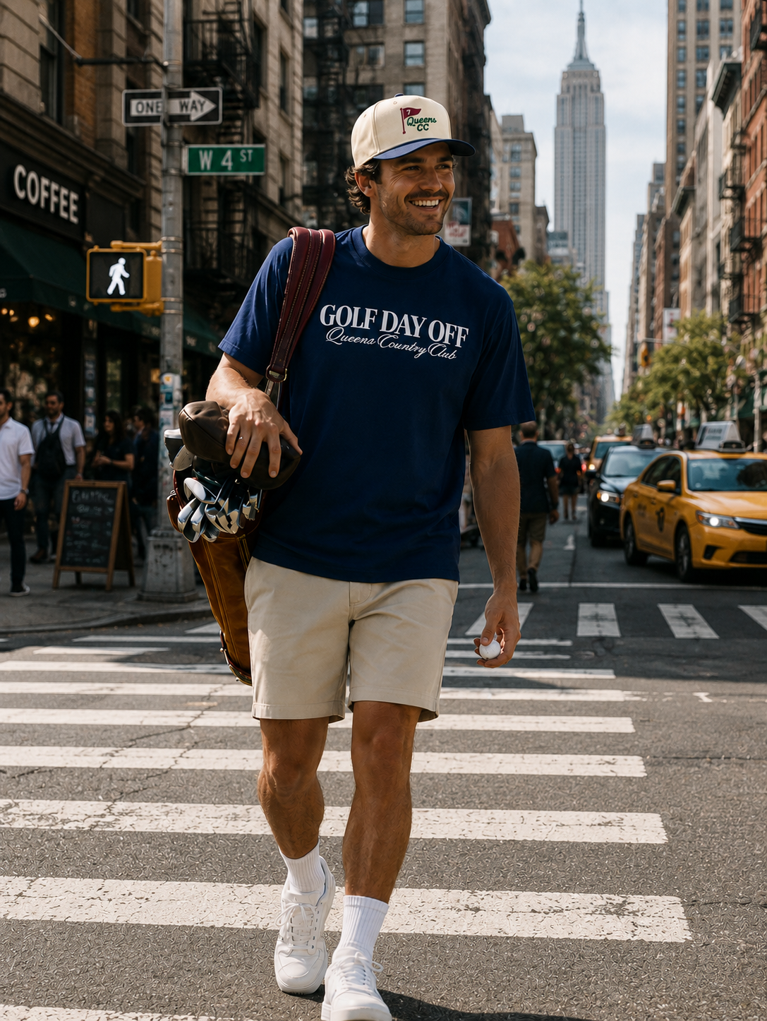Man walking on a city street wearing a navy blue t-shirt with text and beige shorts.