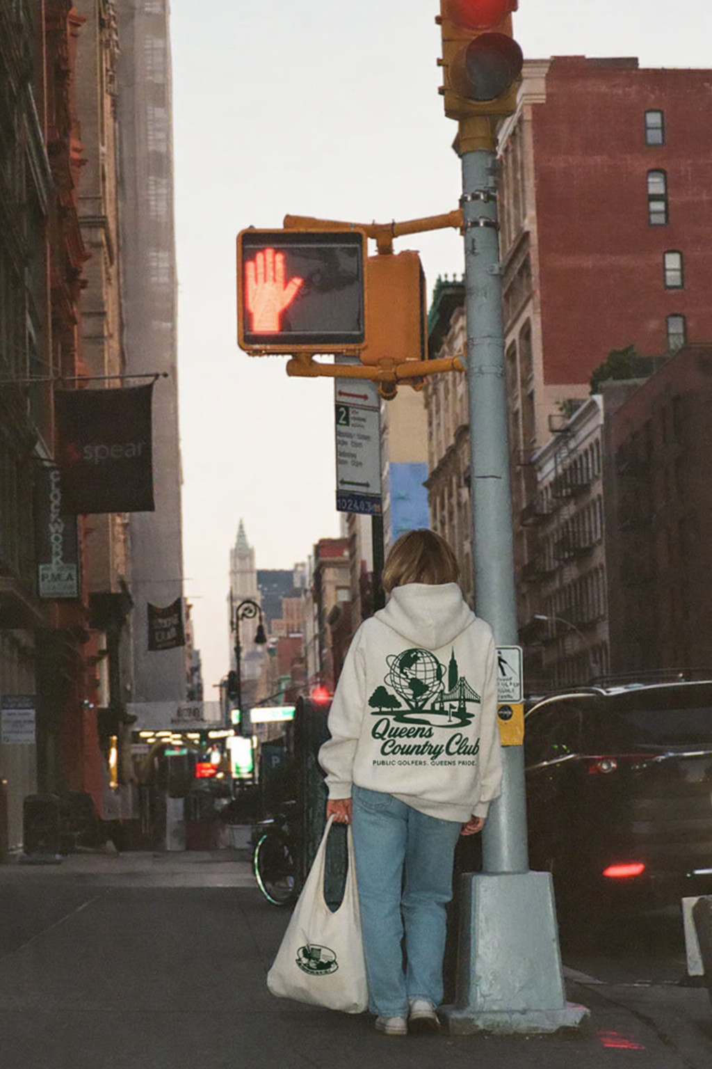 Person walking on a city street with traffic lights and buildings in the background