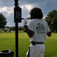 Person holding a golf club with a '18' marker on a golf course