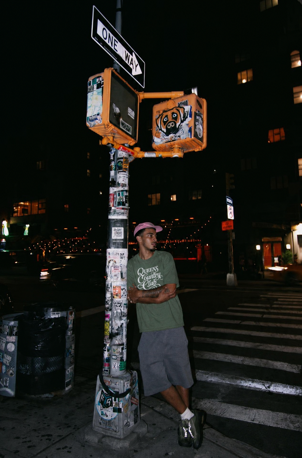 Model wearing a moss QCC Heritage Script heavyweight tee on a New York City street at night